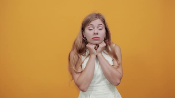Atrakcyjna biała młoda kobieta trzymająca pięści nad podbródkiem, patrząca w kamerę - Materiał filmowy, wideo