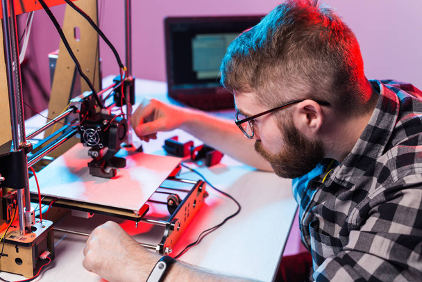 Young male designer engineer using a 3D printer in the laboratory and studying a product prototype, technology and innovation concept - Photo, Image