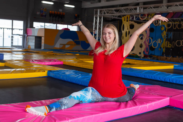 Fitness, sport, uitoefening, stretching en mensen concept-lachende vrouw doet splitst op mat over Gym achtergrond - Foto, afbeelding