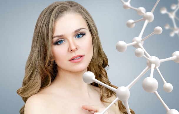 Красива жінка біля ланцюга великих білих молекул
. - Фото, зображення