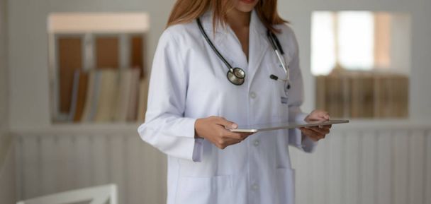 Oříznutý záběr mladé doktorky držící tablet v nemocniční kanceláři  - Fotografie, Obrázek