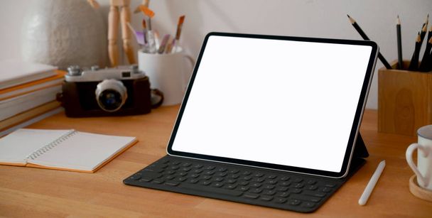 Boş ekran dijital tableti ve ahşap masa üzerindeki ofis malzemeleriyle tasarımcı iş yerinin yakın görüntüsü  - Fotoğraf, Görsel
