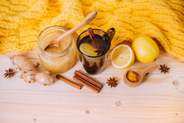 Beker warm water met citroen, honing en gemberwortel. Ingrediënten met gebreide sjaal op een houten ondergrond. Begrip traditionele behandeling. Kopieerruimte - Foto, afbeelding