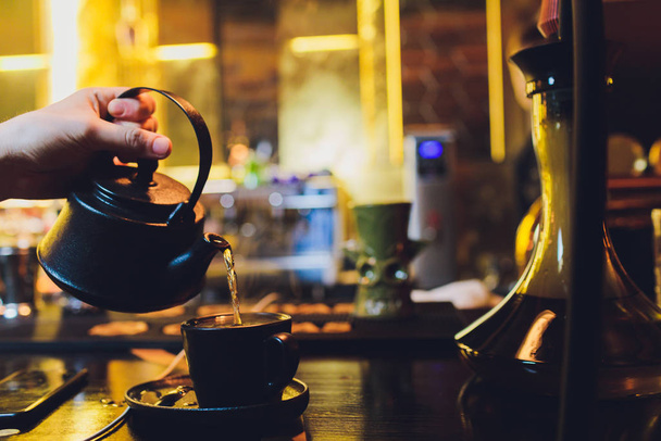 Female hands pouring tea from a teapot closeup. - Fotografie, Obrázek