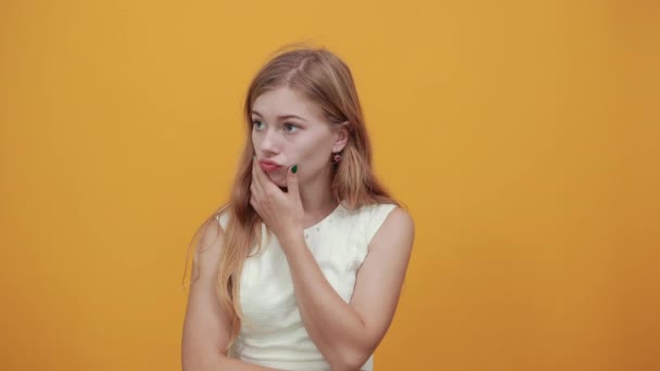 enttäuschte junge kaukasische Frau hält den Finger auf die Wangen, hält die Lippen fest - Filmmaterial, Video