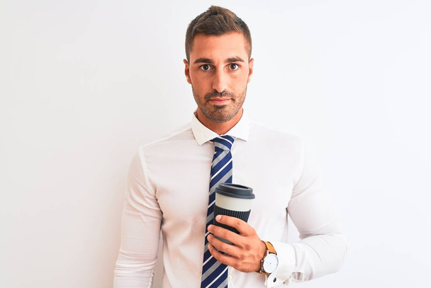 Young handsome business man drinking take away coffee over isolated background with a confident expression on smart face thinking serious - Photo, Image