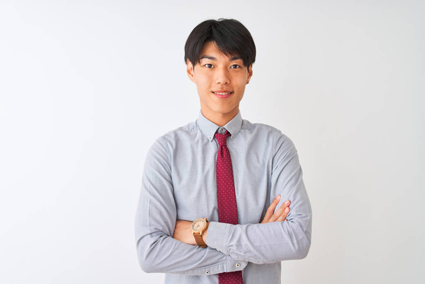 Китайський бізнесмен у вишуканій краватці стоїть над білим фоном і радісно посміхається з перехрещених рук, дивлячись на камеру. Позитивна людина. - Фото, зображення