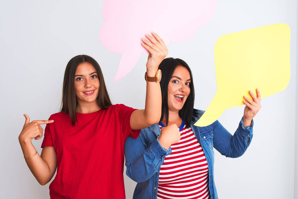 Young beautiful women holding speech bubble standing over isolated white background with surprise face pointing finger to himself - Photo, Image