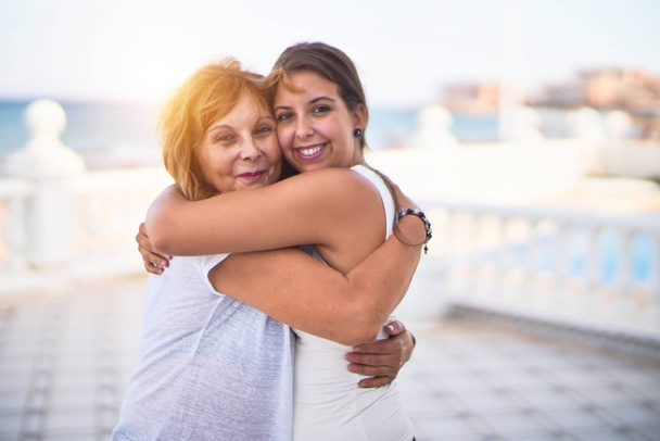 Schöne Mutter und Tochter umarmen sich auf der Terrasse mit glücklichem Gesicht - Foto, Bild