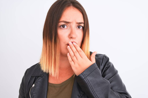 Young beautiful woman wearing t-shirt and jacket standing over isolated white background cover mouth with hand shocked with shame for mistake, expression of fear, scared in silence, secret concept - Photo, Image