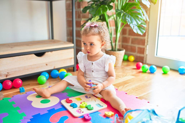 Hermoso bebé caucásico jugando con juguetes en la colorida sala de juegos. Feliz y juguetón en el jardín de infantes
. - Foto, Imagen