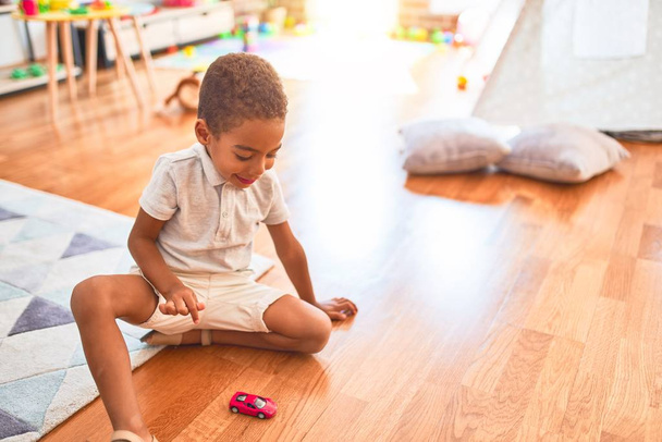 Beautiful african american toddler playing with cars around lots of toys at kindergarten - Foto, Imagen