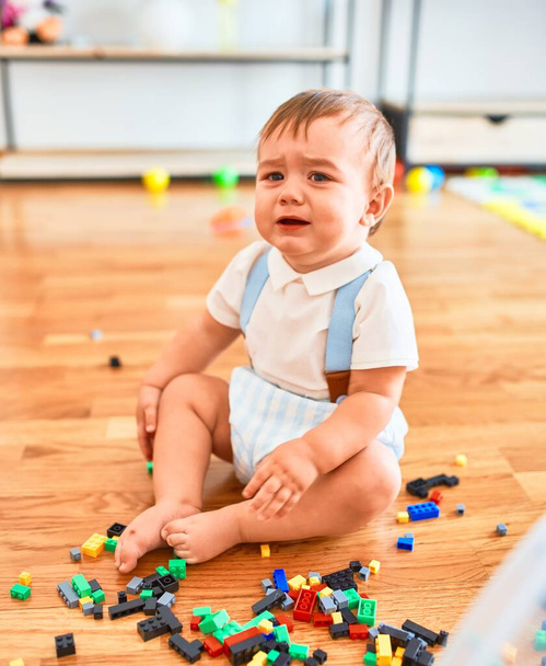 Adorable toddler crying around lots of toys at kindergarten - Foto, Bild