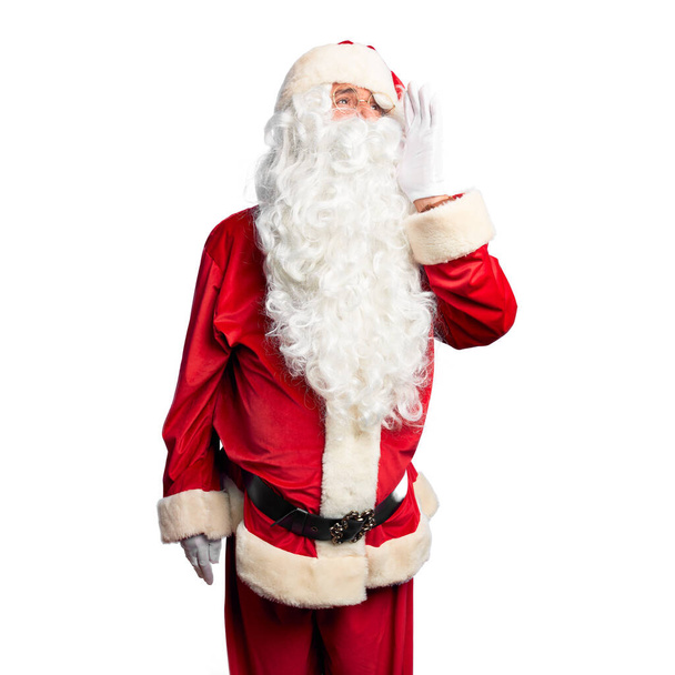 Красивый мужчина средних лет в костюме Санта-Клауса и с бородой, стоя и крича громко в бок с рукой на губах. Концепция коммуникации
. - Фото, изображение