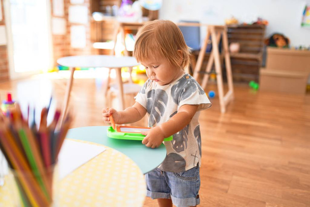 Desenho de criança adorável usando placa digital em torno de lotes de brinquedos no jardim de infância
 - Foto, Imagem