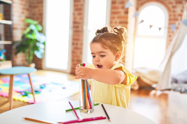 Hermoso niño de pie sosteniendo lápices de colores en el jardín de infantes
 - Foto, Imagen