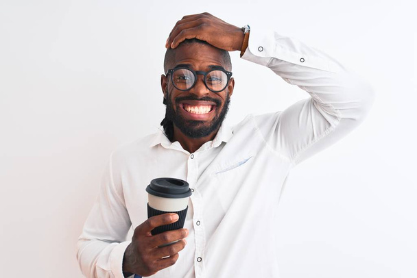 Afrikanisch-amerikanischer Geschäftsmann mit Zöpfen, Kaffee trinkend vor isoliertem weißen Hintergrund, gestresst mit der Hand auf dem Kopf, schockiert vor Scham und Überraschung, wütend und frustriert. Angst und Verärgerung wegen Fehlern. - Foto, Bild
