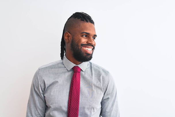 Empresário afro-americano com tranças usando gravata em pé sobre fundo branco isolado olhando para o lado com sorriso no rosto, expressão natural. Rindo confiante
. - Foto, Imagem