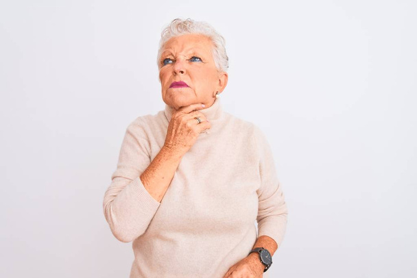 Mujer mayor de cabello gris que usa suéter de cuello alto de pie sobre un fondo blanco aislado Tocando el cuello doloroso, dolor de garganta para la gripe, la clod y la infección
 - Foto, Imagen