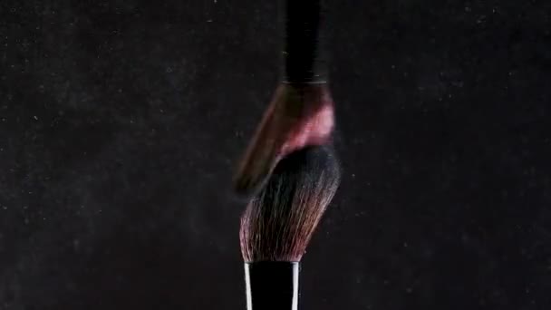 Two Soft cosmetic brushes release a cloud of colored smoke from bright eyeshadow and powder, - Video