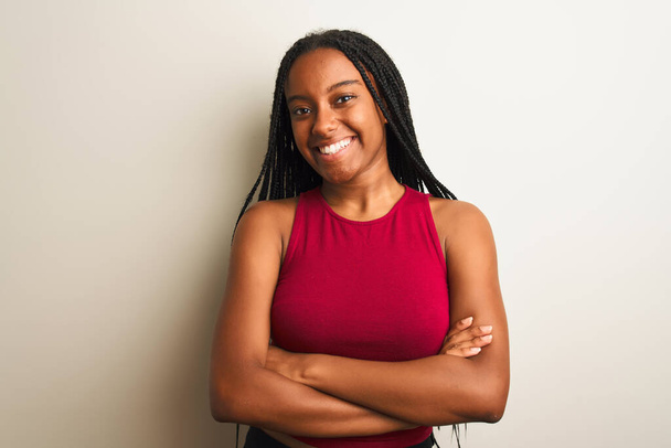 Femme afro-américaine portant un t-shirt décontracté rouge debout sur un fond blanc isolé heureux visage souriant avec les bras croisés regardant la caméra. Personne positive
. - Photo, image