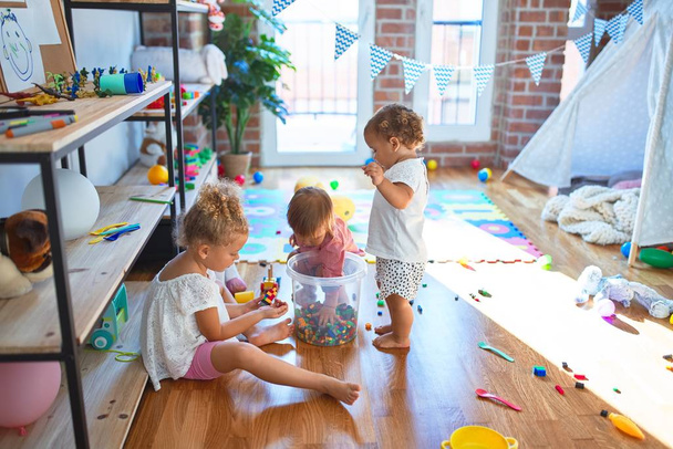 Schattige peuters spelen rond veel speelgoed op de kleuterschool - Foto, afbeelding