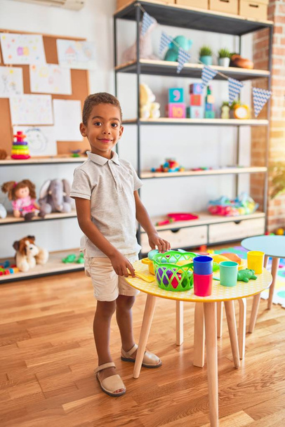 Beau bambin afro-américain jouant avec de la nourriture en plastique et des couverts jouet à la maternelle
 - Photo, image