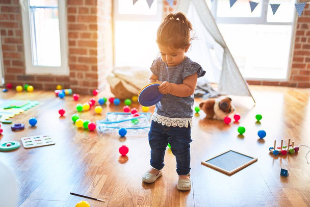 Beautiful toddler holding colorful plastic dishes standing at kindergarten - Photo, Image