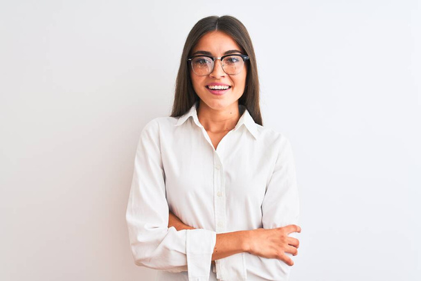 Young beautiful businesswoman wearing glasses standing over isolated white background happy face smiling with crossed arms looking at the camera. Positive person. - Φωτογραφία, εικόνα