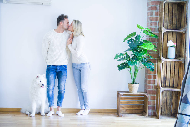 jong mooi paar met hond kussen staan in nieuw huis - Foto, afbeelding