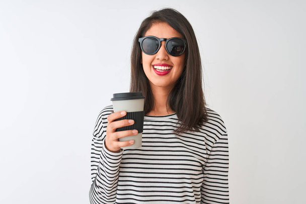 Femme chinoise portant des lunettes de soleil boire emporter café sur fond blanc isolé avec un visage heureux debout et souriant avec un sourire confiant montrant les dents
 - Photo, image