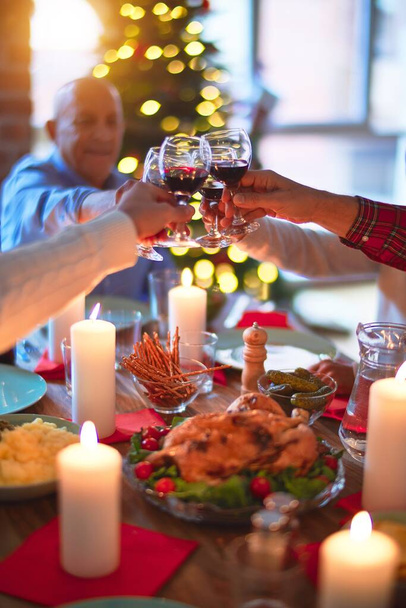 Όμορφη οικογένεια χαμογελά ευτυχισμένη και αυτοπεποίθηση. Τρώγοντας ψητό γαλοπούλα και ψήσιμο με φλιτζάνι κρασί γιορτάζει τα Χριστούγεννα στο σπίτι - Φωτογραφία, εικόνα