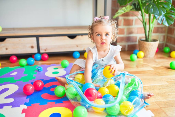 Beautiful caucasian infant playing with toys at colorful playroom. Happy and playful wth colorful balls at kindergarten. - Fotografie, Obrázek