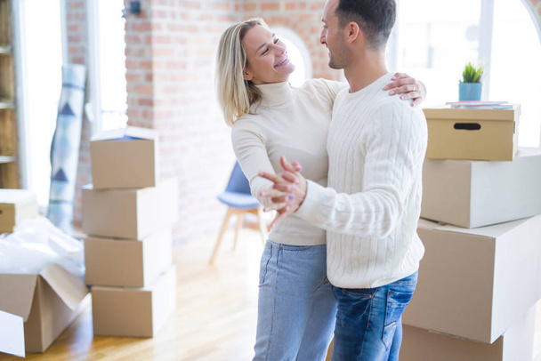 Joven hermosa pareja bailando en un nuevo hogar alrededor de cajas de cartón
 - Foto, Imagen