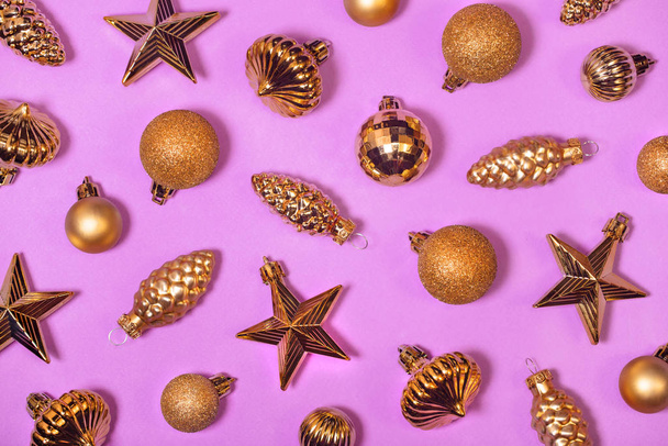 Glossy golden Xmas tree decorations background. Vintage shiny Christmas ornaments on magenta. Old fashioned star shaped toys, baubles and cones. Horizontal New Year decorative backdrop for banner. - Фото, зображення