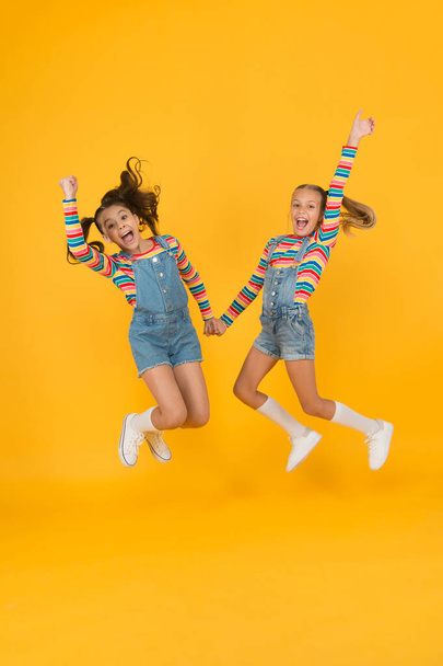 sense of freedom. summer vacation together. free and energetic beauty. happy childhood. real friendship. best friends forever. small sisters have fun. little girls jump yellow background - Photo, image