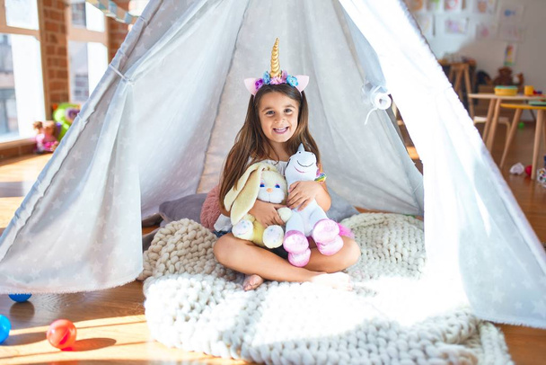 Adorable toddler sitting on the floor inside tipi around lots of toys at kindergarten - Foto, immagini