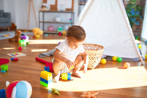 Красивый ребенок играет со строительными блоками вокруг много игрушек в детском саду
 - Фото, изображение
