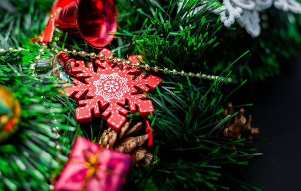 Dekoratif kar taneleri ve siyah arka planda oyuncaklarla süslenmiş Noel çelengi - Fotoğraf, Görsel