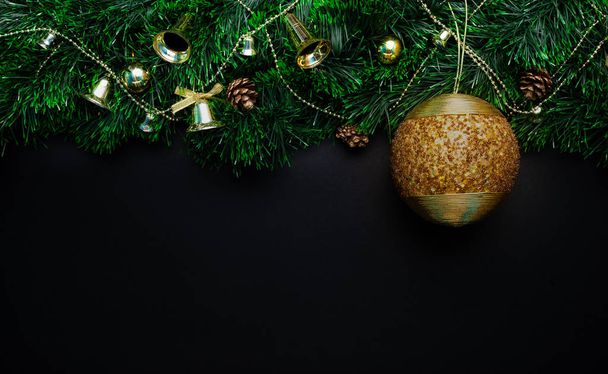 Christmas wreath decorated with a Big golden ball of beads and bells, cones, beads on a black background - Foto, Imagen