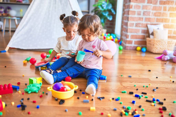 Adorables tout-petits jouant des repas en utilisant des aliments en plastique et des couverts jouet à la maternelle
 - Photo, image