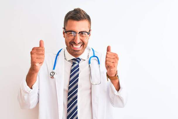Young handsome doctor man wearing stethoscope over isolated background excited for success with arms raised and eyes closed celebrating victory smiling. Winner concept. - Photo, Image