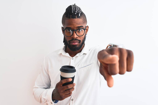 Afro-Amerikaanse zakenman met vlechten die koffie drinken over geïsoleerde witte achtergrond wijzend met de vinger naar de camera en naar jou, handteken, positief en zelfverzekerd gebaar van voren - Foto, afbeelding