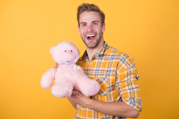 Valentines day gift. Man hug soft toy. Make surprise concept. Positive vibes. Cute teddy bear toy. Softness tenderness. Playful adult. Cute and romantic. Bearded hipster play toy yellow background - Foto, immagini
