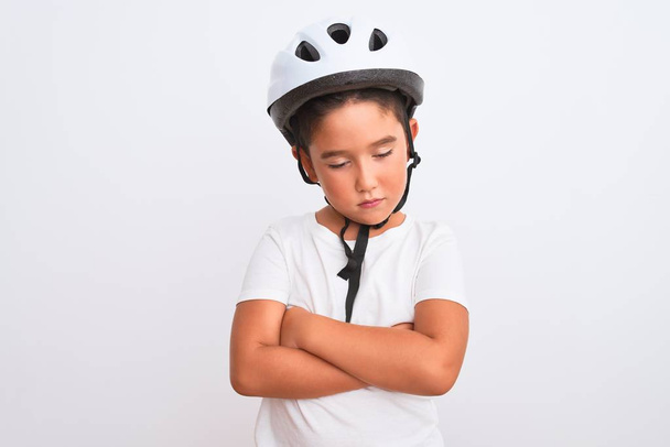 Красивый мальчик в велосипедном шлеме безопасности стоит на изолированном белом фоне скептически и нервно, неодобрительное выражение лица со скрещенными руками. Отрицательное лицо
. - Фото, изображение