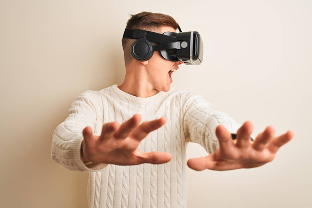Young handsome teenager boy playing virtual reality game using goggles - Fotó, kép
