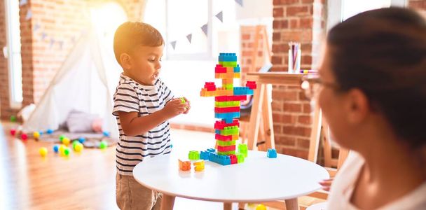 Hermoso maestro y niño jugando con bloques de construcción torre de construcción en el jardín de infantes
 - Foto, imagen