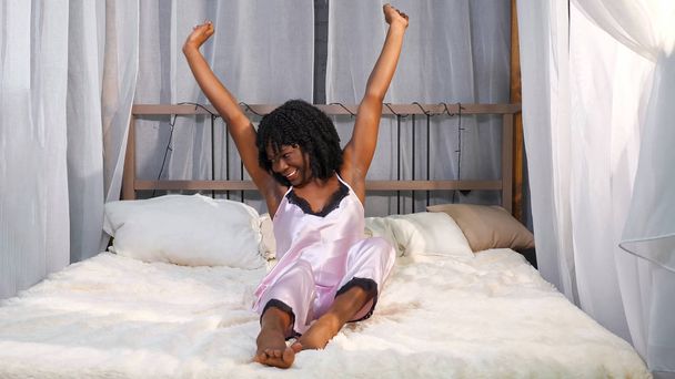 usmívající se Afroameričanka se probudí a protáhne se na posteli - Fotografie, Obrázek