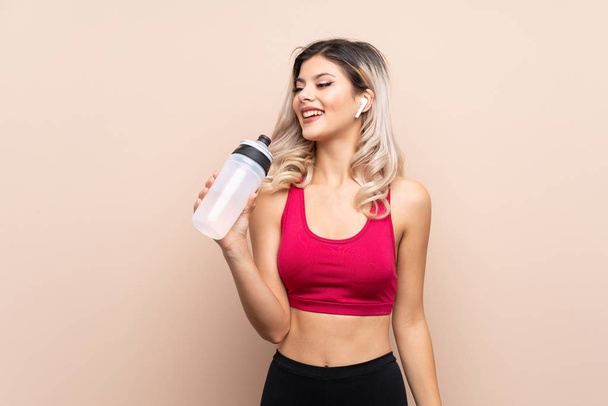 Teenager sport girl over isolated background with sports water bottle - Fotó, kép