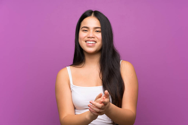 Young teenager Asian girl over isolated purple background applauding - Foto, Imagen